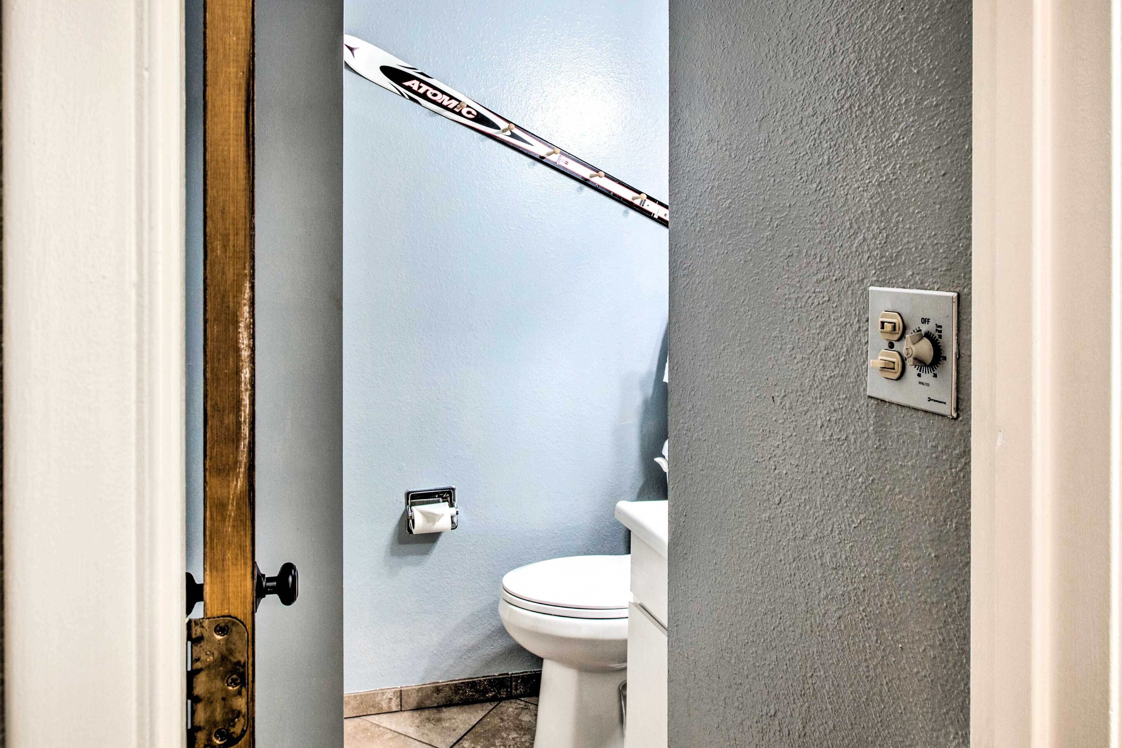 Un baño con inodoro, dispensador de toallas y un interruptor de luz en la pared.