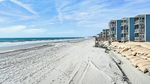 A beach with a row of blue buildings, sandy beach, and footprints in the sand.