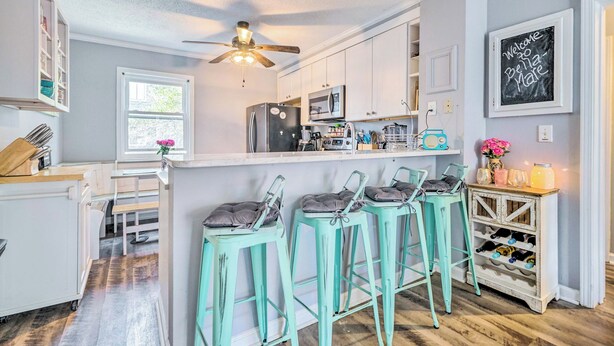 A kitchen with white cabinets, a ceiling fan, and a bar area with turquoise stools.