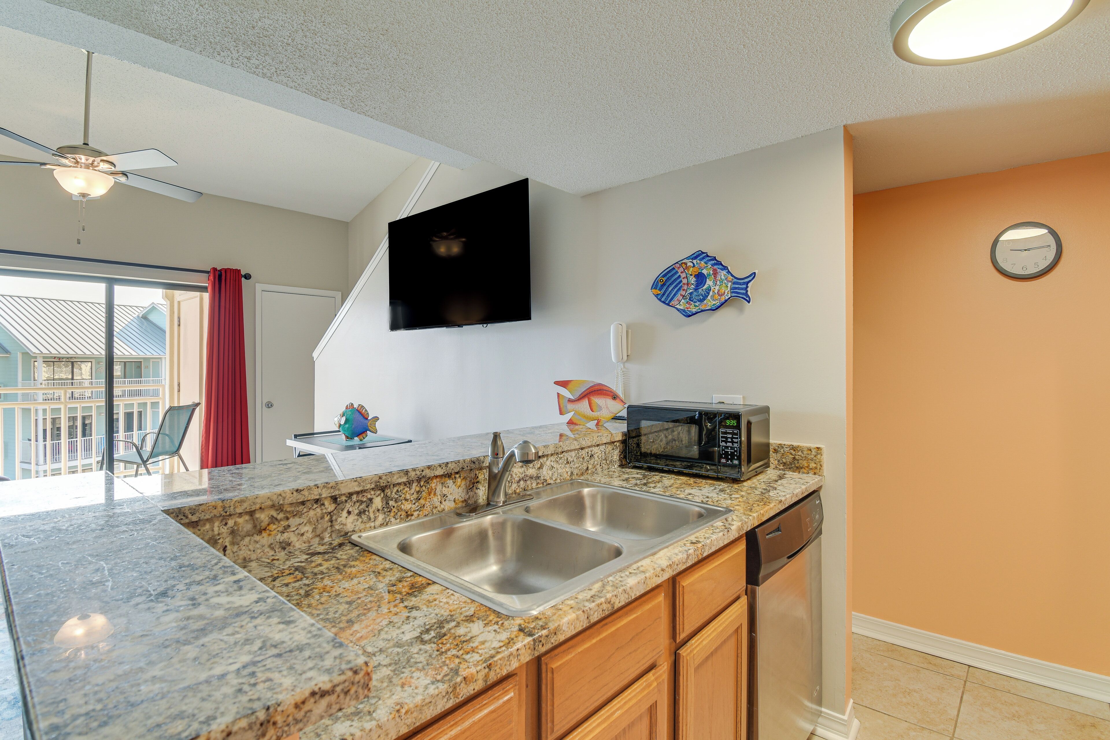A kitchen with granite countertops, stainless steel sink, and a microwave.