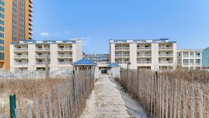 A pathway leading to a building with multiple balconies and a covered area.