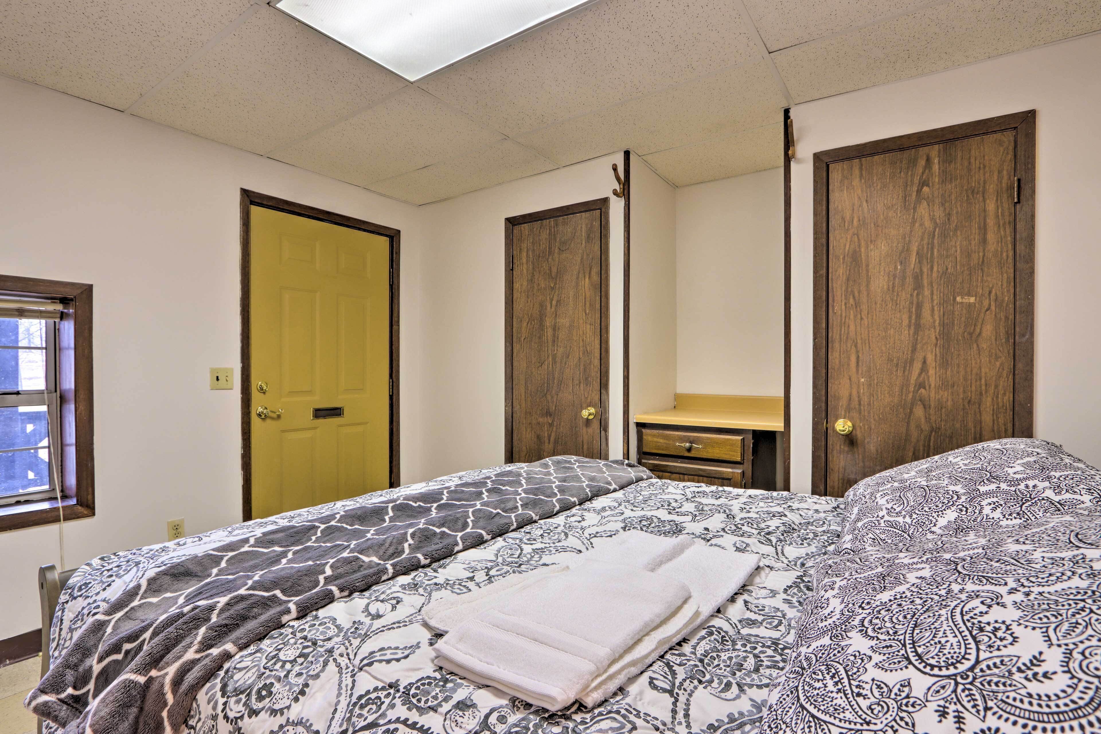 Une chambre à coucher avec un lit, deux portes, une fenêtre et une table de chevet.