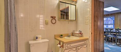 A bathroom with a toilet, sink, vanity, and mirror.