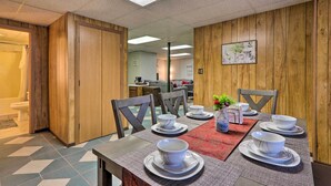 Un coin repas avec un mur en bois, un sol carrelé et une table dressée avec des bols et des assiettes blancs.