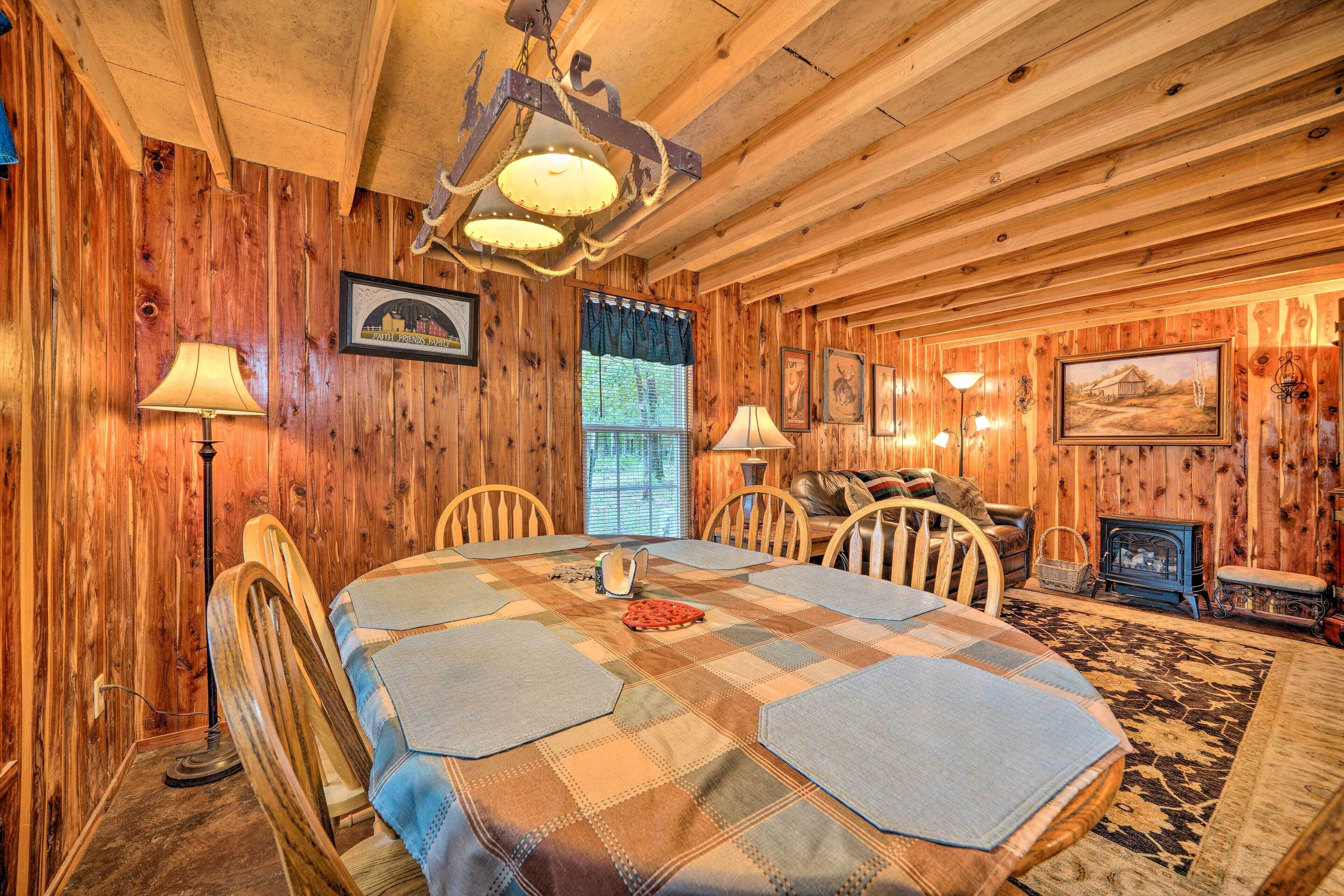A wooden-paneled room with a large table, chairs, and a fireplace.