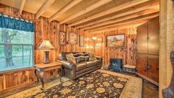 A rustic wooden interior with a leather sofa, a patterned rug, and a cabinet.