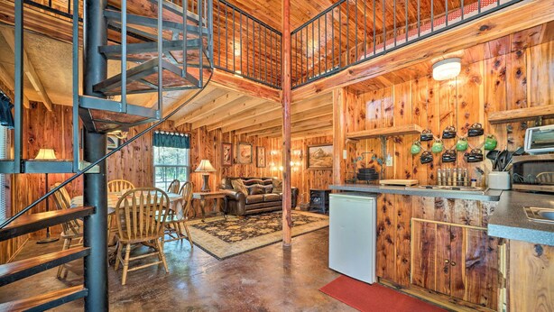 A rustic cabin interior with a wooden staircase, a dining area, a kitchen, and a living room. - Peaceful 'black Fork Cabin 1' - Fish On-site! (Nashoba)