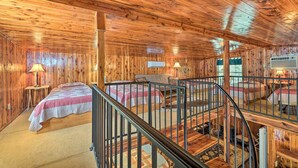 A cabin with wooden walls and ceilings, a staircase, and two beds with red and white bedding. - Peaceful 'black Fork Cabin 1' - Fish On-site! (Nashoba)