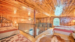 A log cabin interior with two beds, a wooden ceiling, and a large window. - Peaceful 'black Fork Cabin 1' - Fish On-site! (Nashoba)