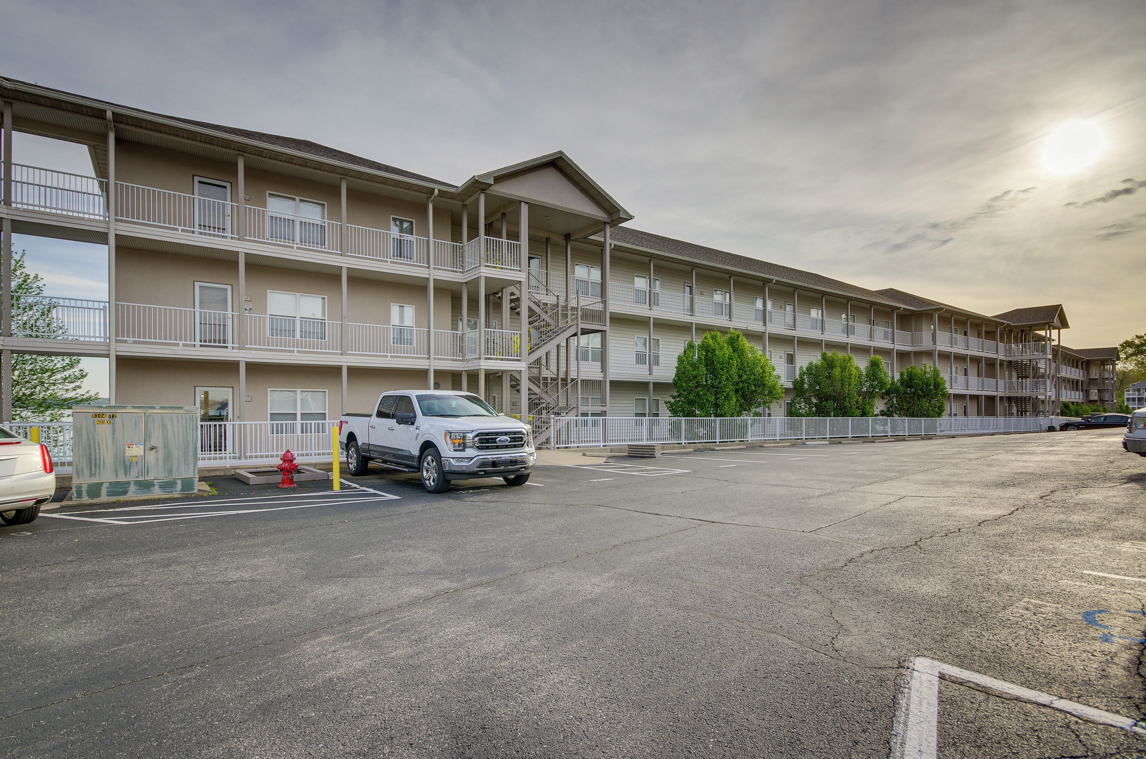 A multi-story motel with balconies, a parking lot, and a red fire hydrant.