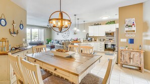 Une cuisine spacieuse avec des meubles blancs, une table à manger en bois et des luminaires suspendus.