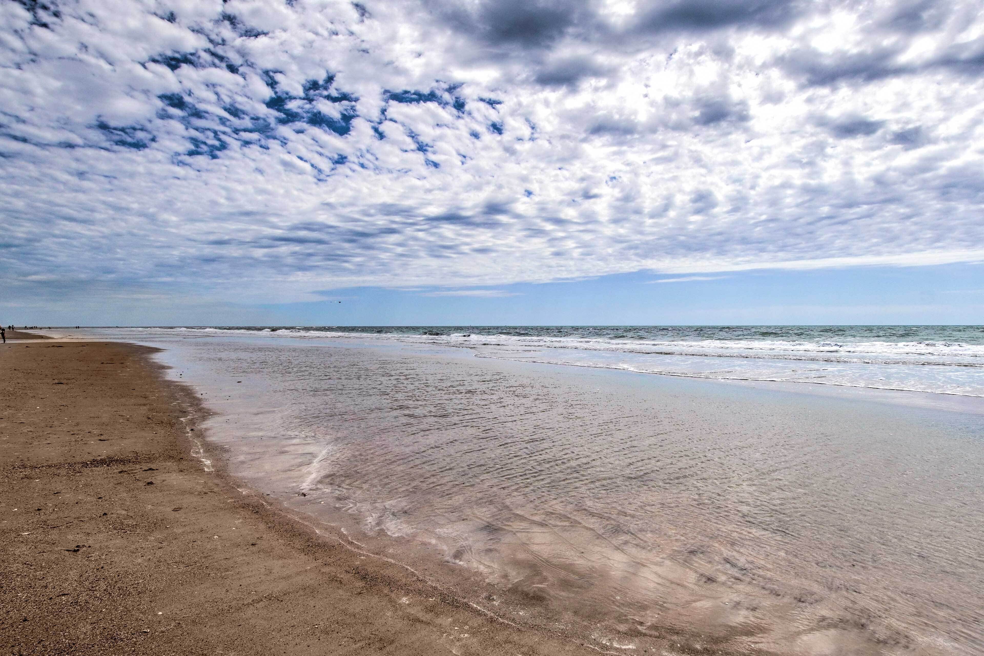 A beach with a wide sandy shore and gentle waves.