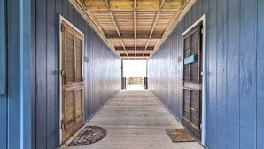 A long hallway with wooden floors and blue walls, leading to a bright exit. - North Topsail Beach Condo w/ Balcony! (Sneads Ferry)