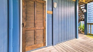 A wooden door with horizontal louvered panels, a blue exterior wall, and a wooden deck. - North Topsail Beach Condo w/ Balcony! (Sneads Ferry)