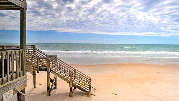 A wooden staircase leading to a beach with a 'KEEP OFF' sign, a clear sky, and calm ocean waves. - North Topsail Beach Condo w/ Balcony! (Sneads Ferry)