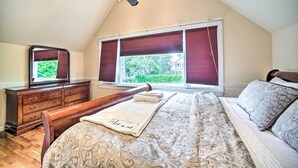 Une chambre à coucher avec un lit, une commode, un miroir et une fenêtre avec des stores.