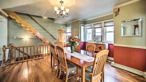 Un coin repas avec une table en bois, des chaises, un vase de fleurs et un escalier.