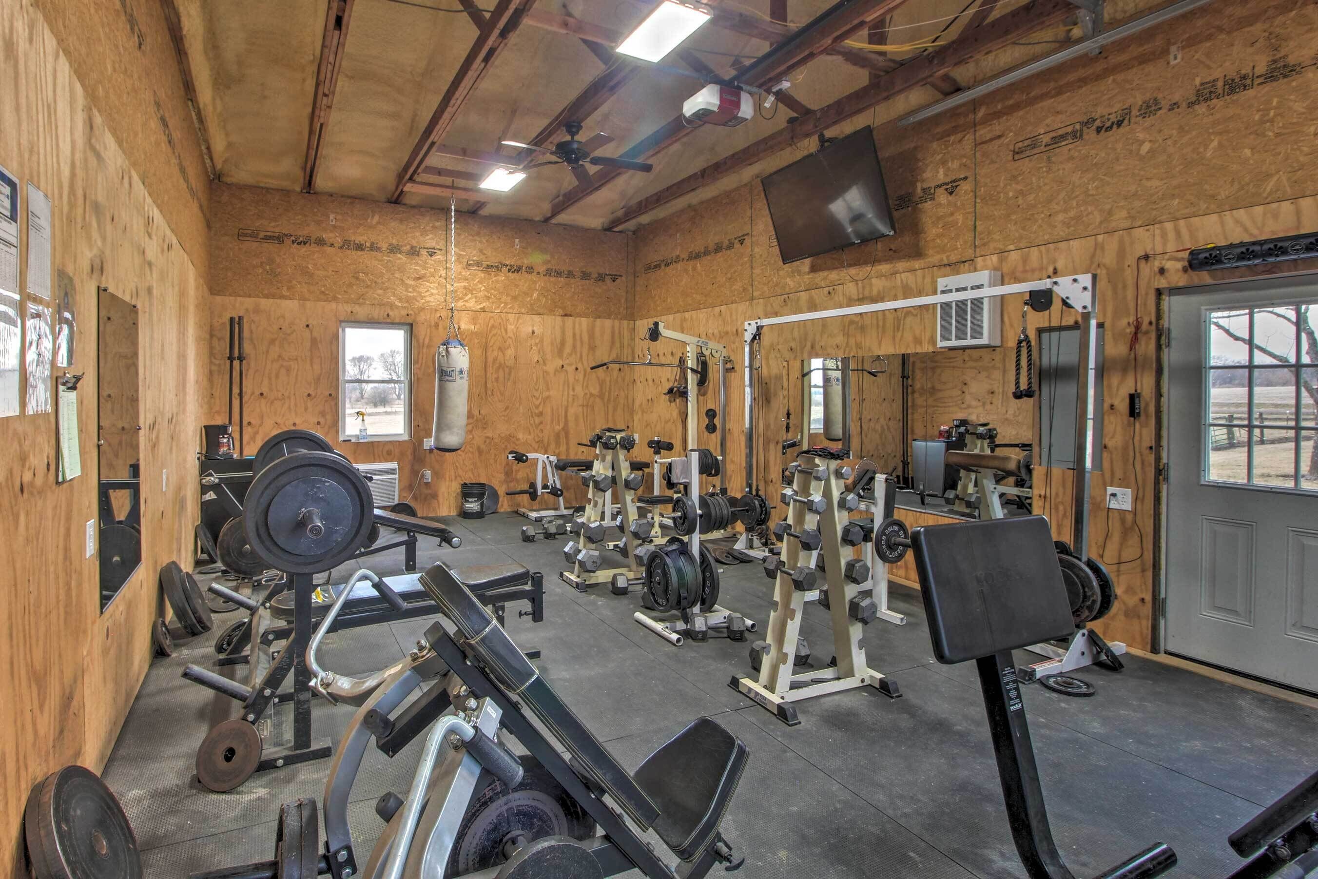 A gym with various weightlifting equipment, a ceiling fan, and a large mirror.