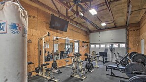A gym with various weightlifting equipment, mirrors, and a punching bag. - Pet-friendly Vacation Rental in Braymer! (Braymer)