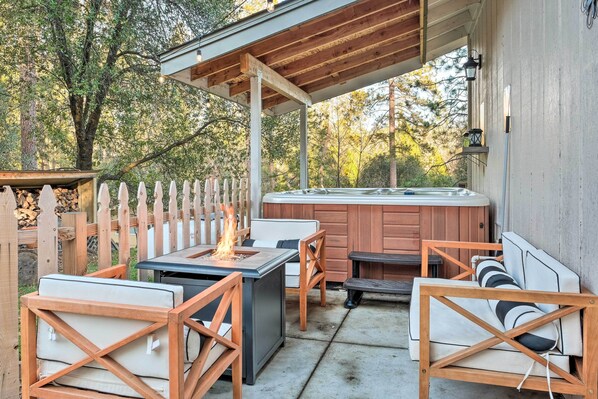 Relax in a serene outdoor space with a hot tub, comfortable seating, and a shaded pergola.