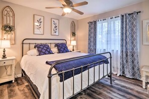 Classic bed frame, framed botanical prints, and a wooden floor create a serene atmosphere.