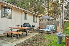 Enjoy al fresco dining and relaxation in this serene backyard oasis with a grill, seating area, and charming umbrella.
