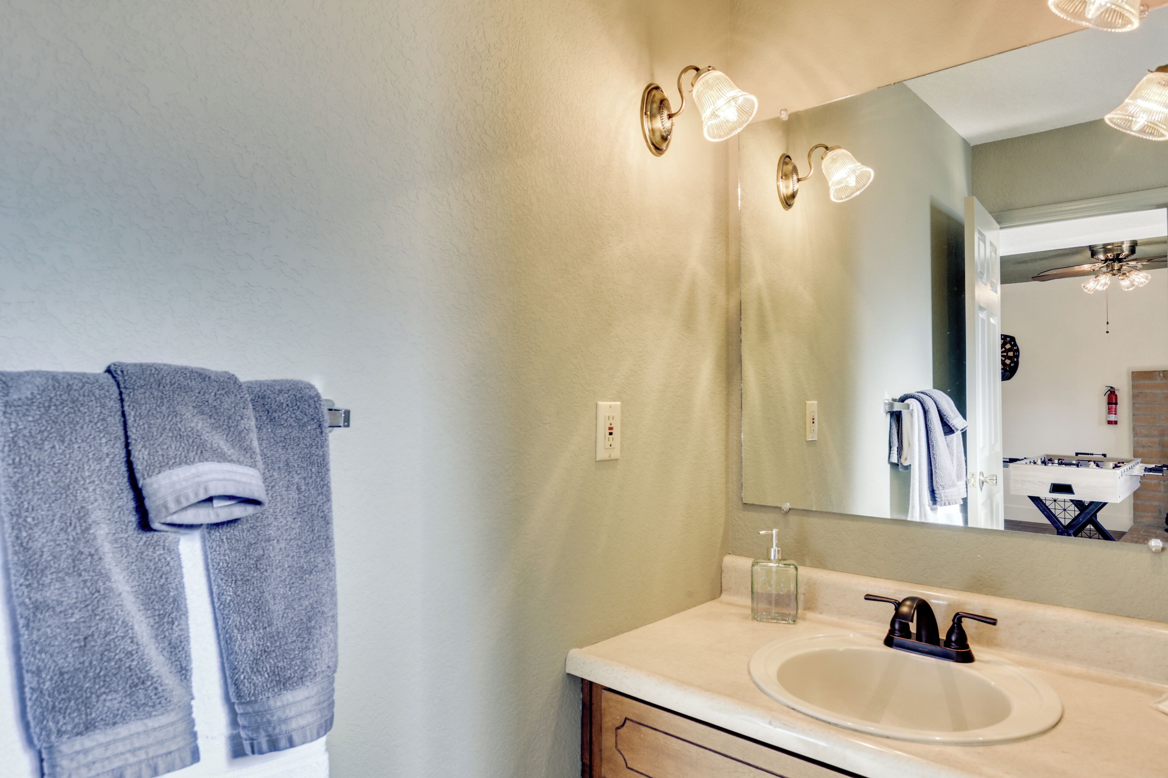 A bathroom with a sink, mirror, towel rack, and light fixtures.
