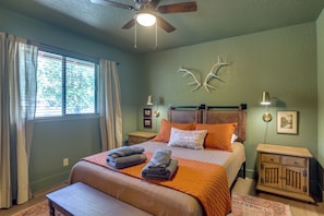 A bedroom with a bed, a nightstand, a wooden cabinet, a ceiling fan, and a window with curtains. - Pet-friendly Escape w/ Game Room & Fire Pit! (North Fork)