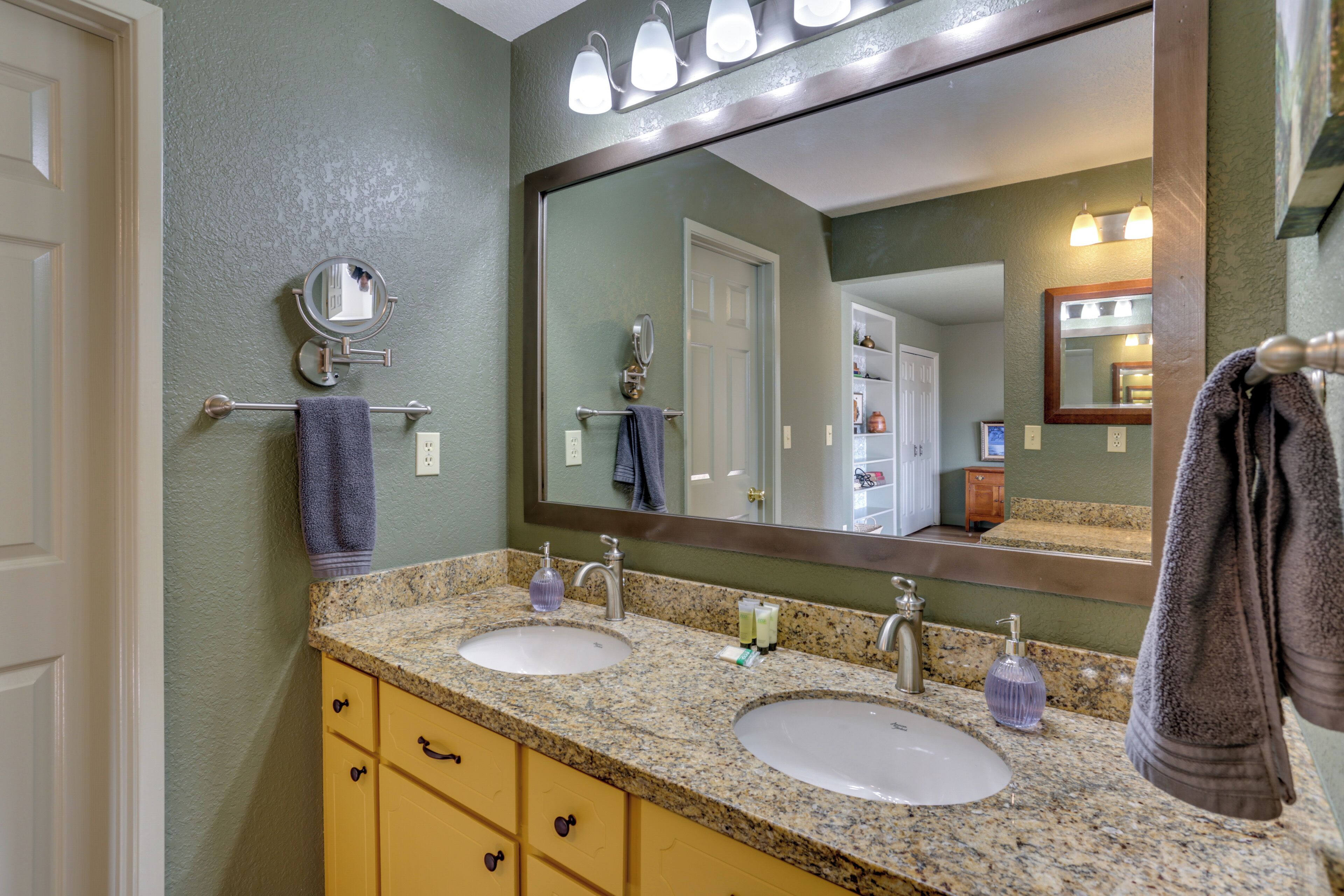 A bathroom with two sinks, a mirror, and a towel rack.