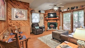 A cozy living room with a fireplace, a dining area with a wooden table and chairs, and a comfortable seating area with a sofa and ottoman.