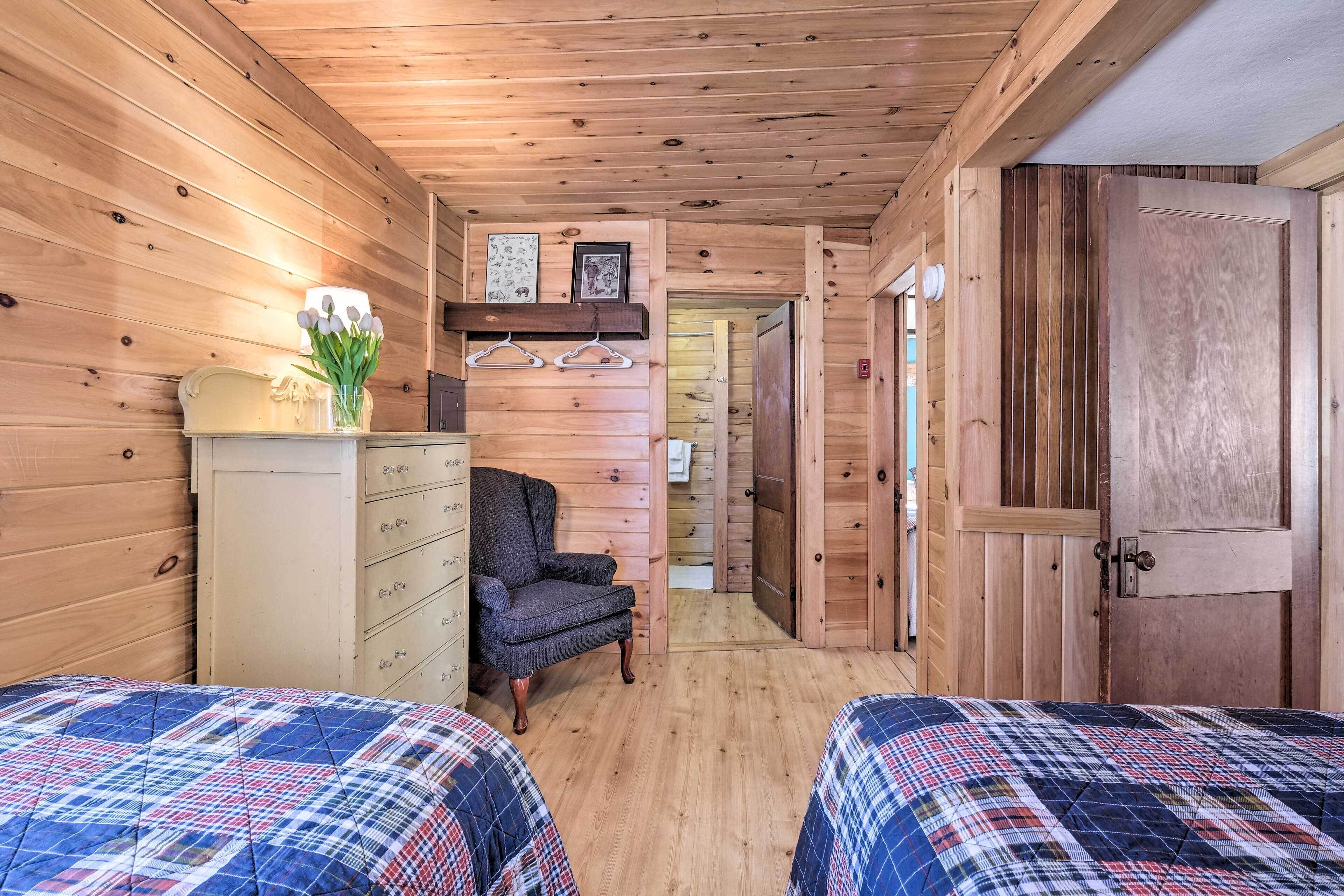 Une chambre confortable dans un chalet, avec deux lits, une commode, une chaise et des murs en bois.