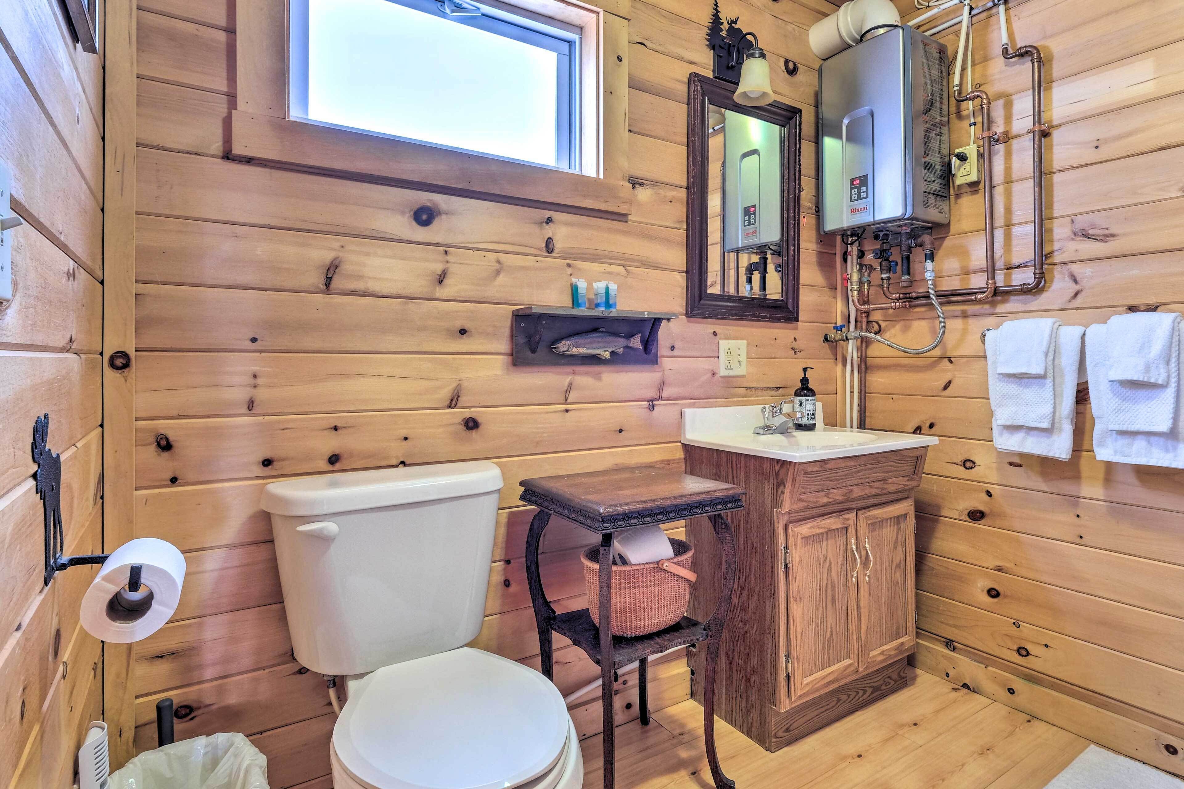 Baño de cabaña de madera con inodoro, lavamanos y un calentador.