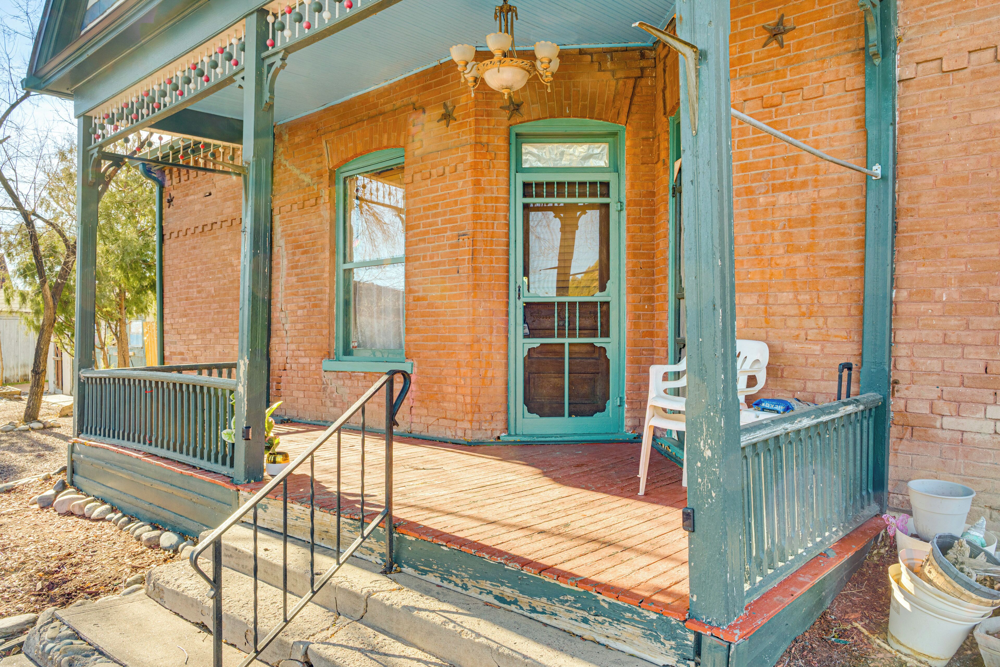 A porch with a green railing, a white chair, and a door with a window.