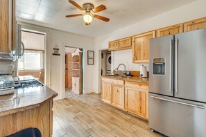 A kitchen with wooden cabinets, a stainless steel refrigerator, a built-in oven, and a ceiling fan. - Walk to Royal Gorge Railroad! Colorado Base Camp (Canon City)