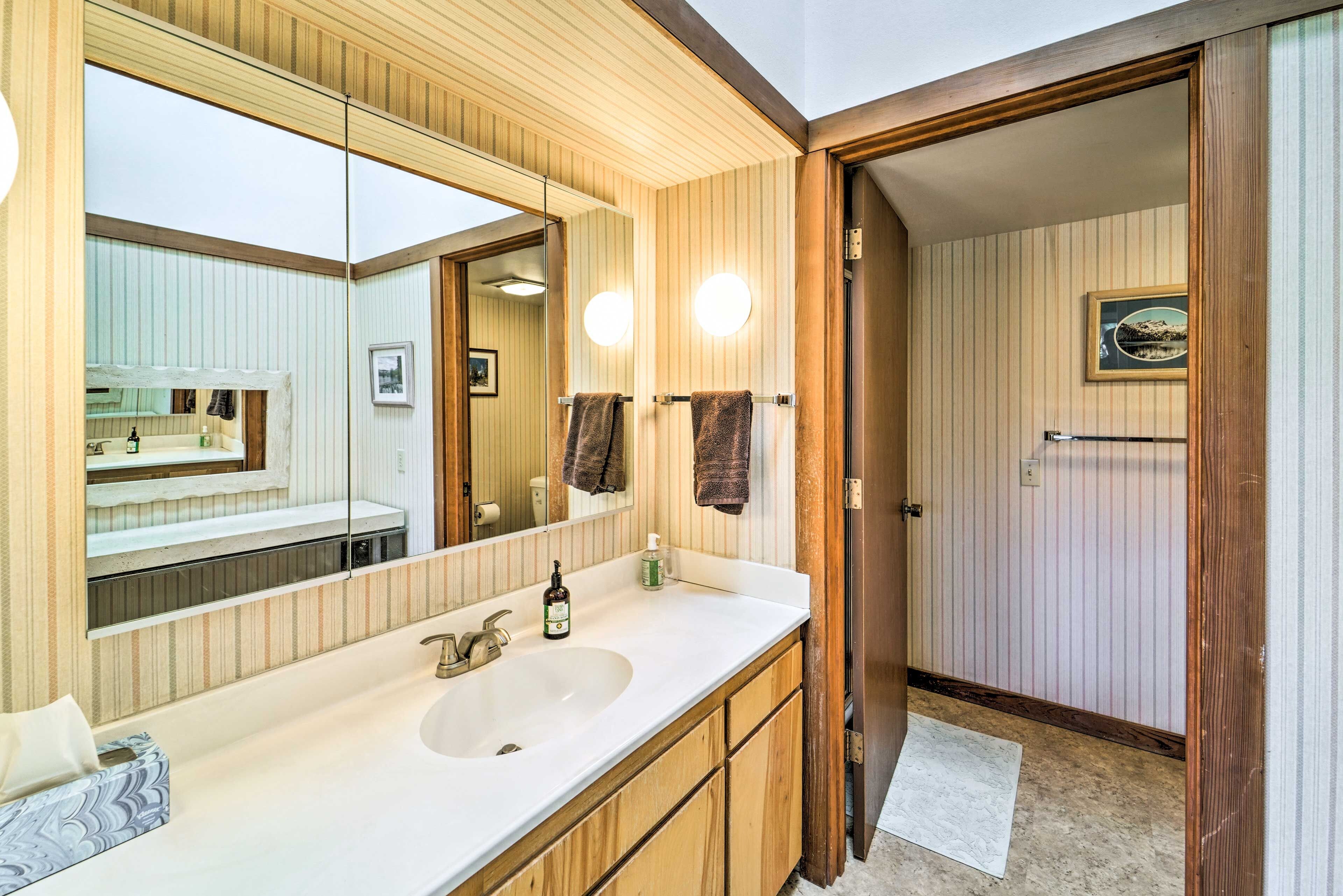 A bathroom with a large mirror, wooden vanity, and a sink.