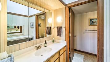 A bathroom with a large mirror, wooden vanity, and a sink.