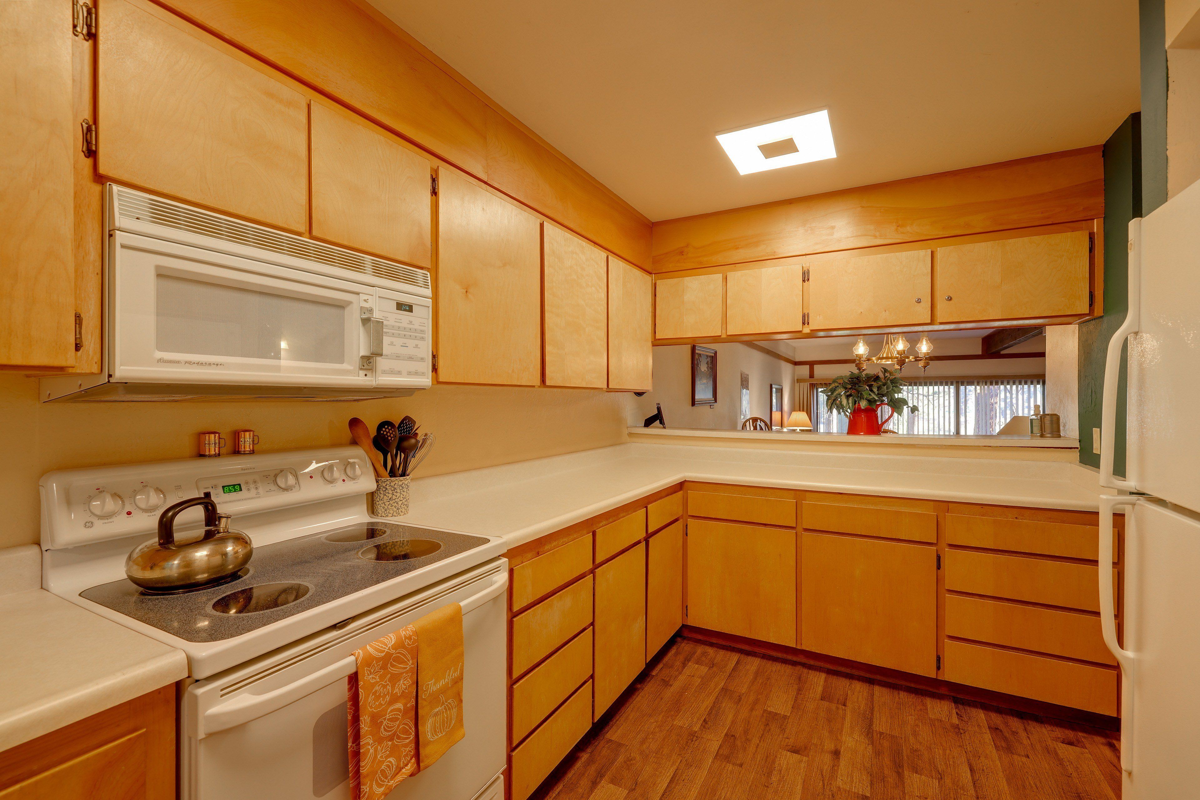 A kitchen with wooden cabinets, a microwave, stove, and a refrigerator.