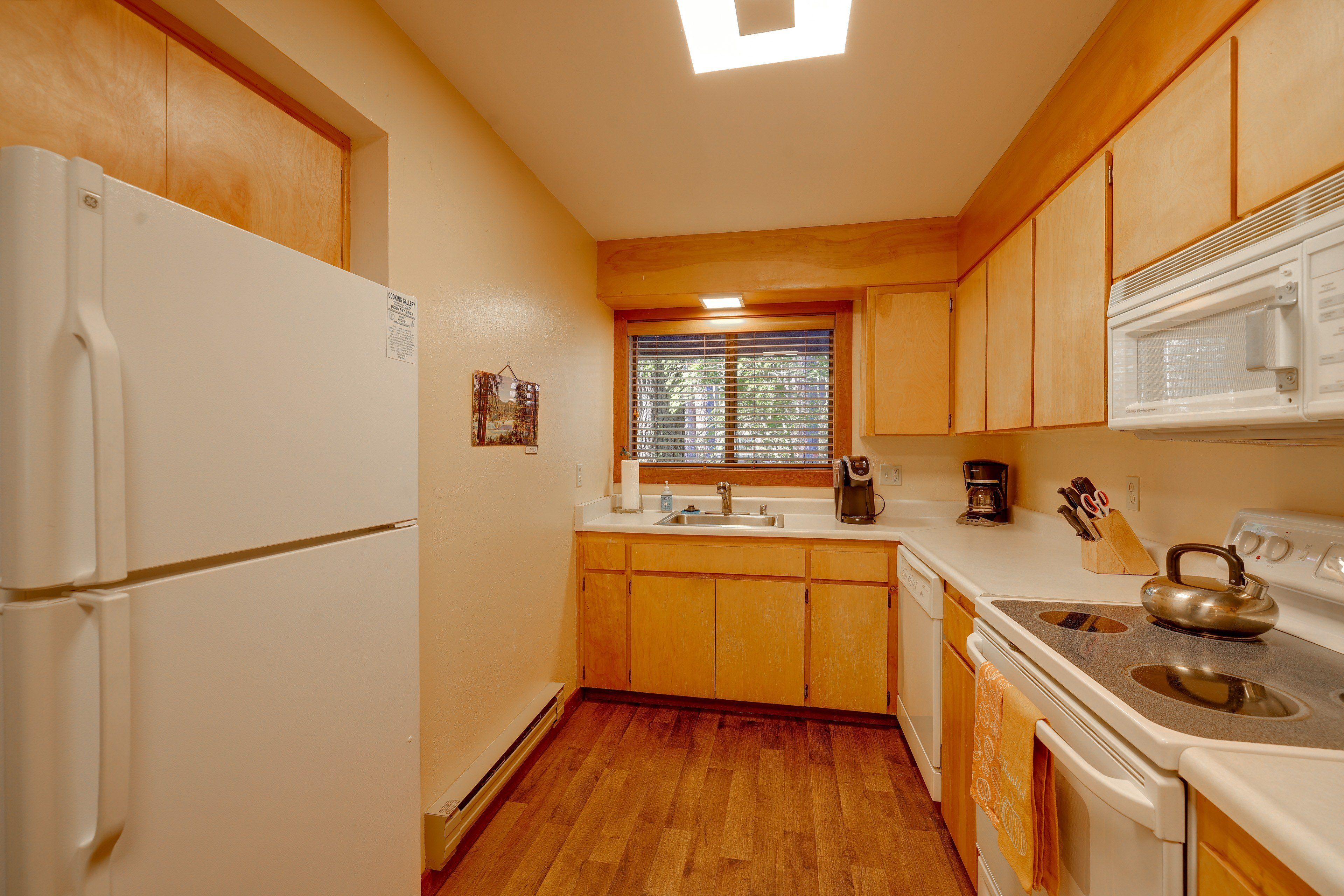 A compact kitchen with wooden cabinets, a refrigerator, a stove, and a microwave.