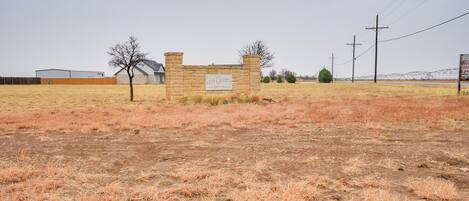 Señal de Lion Country Estates con un muro de piedra y un campo árido en primer plano.