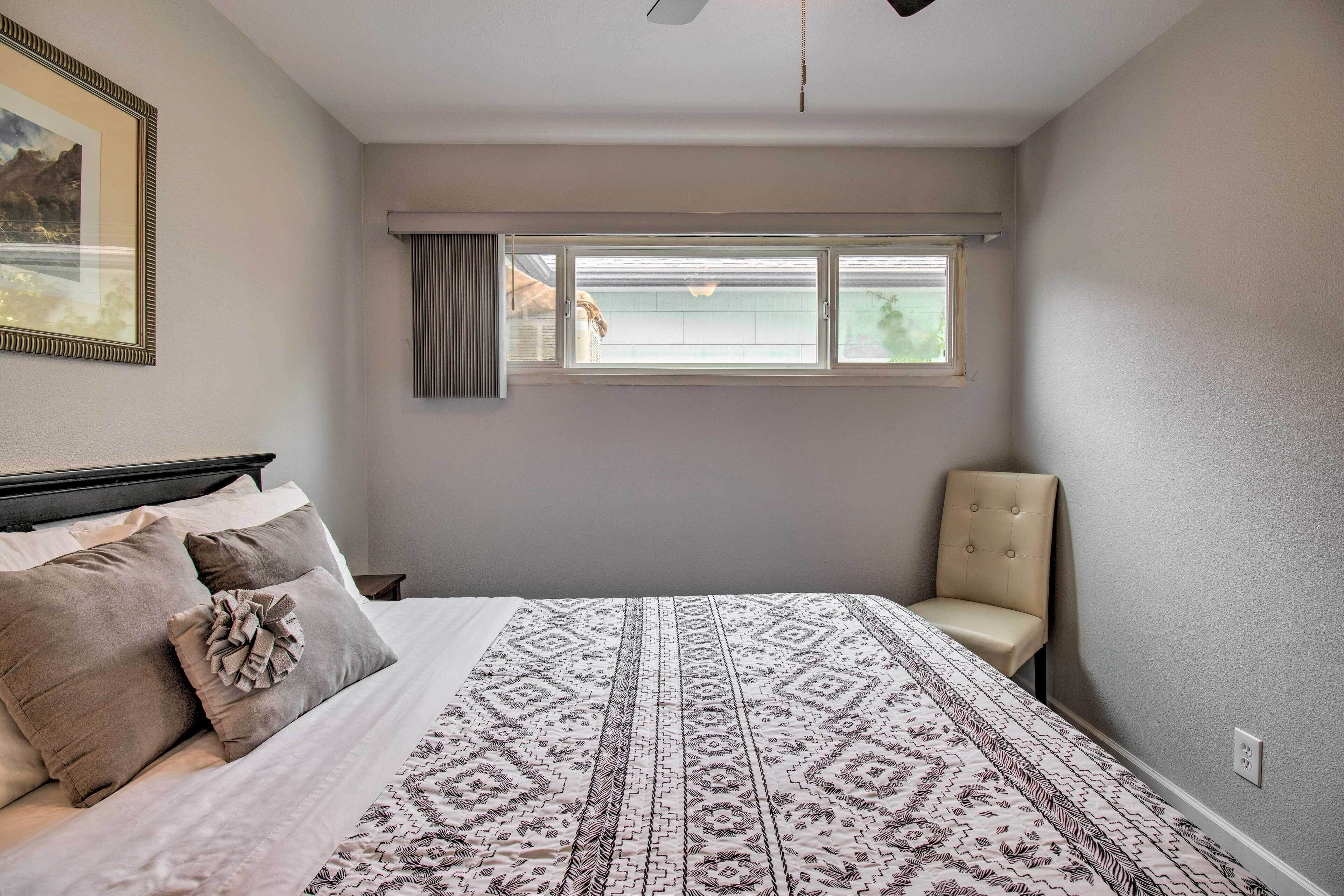 A bedroom with a bed, a window, and a chair.
