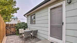 A patio with a table and chairs, a wooden fence, and a house with a garage door.