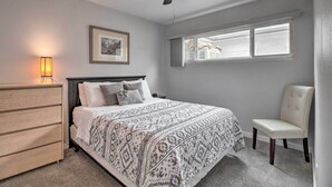 A bedroom with a bed, a dresser, a chair, a ceiling fan, a window, and a framed picture on the wall. - Ski, Hike & Unwind: Cozy Carson City Duplex! (Carson City)