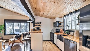 A modern kitchen with wooden ceiling, large windows, and stainless steel appliances. - Pocono Lake Cabin w/ Hot Tub & Resort Amenities! (Pocono Lake)