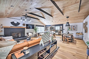 Un vaste espace de vie doté d’une cheminée, d’un canapé en cuir, d’une table à manger en bois et d’une cuisine à l’arrière-plan.