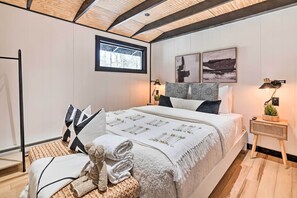 A bedroom with a large bed, a window, a bedside table with a lamp, and a wall-mounted artwork. - Pocono Lake Cabin w/ Hot Tub & Resort Amenities! (Pocono Lake)