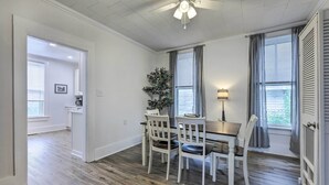 A dining area with a table and chairs, a ceiling fan, and a window with curtains.