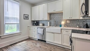 A kitchen with white cabinets, a stainless steel dishwasher, and a patterned backsplash.