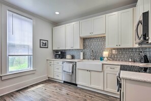 A kitchen with white cabinets, a stainless steel dishwasher, and a patterned backsplash.