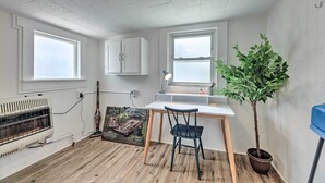 A small, well-lit room with a desk, chair, and a potted plant.