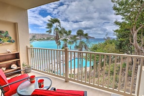 A balcony with a pool view, red chairs, and a glass table. - Saint Thomas Condo w/ Ocean Views, Walk to Beach! (St. Thomas)